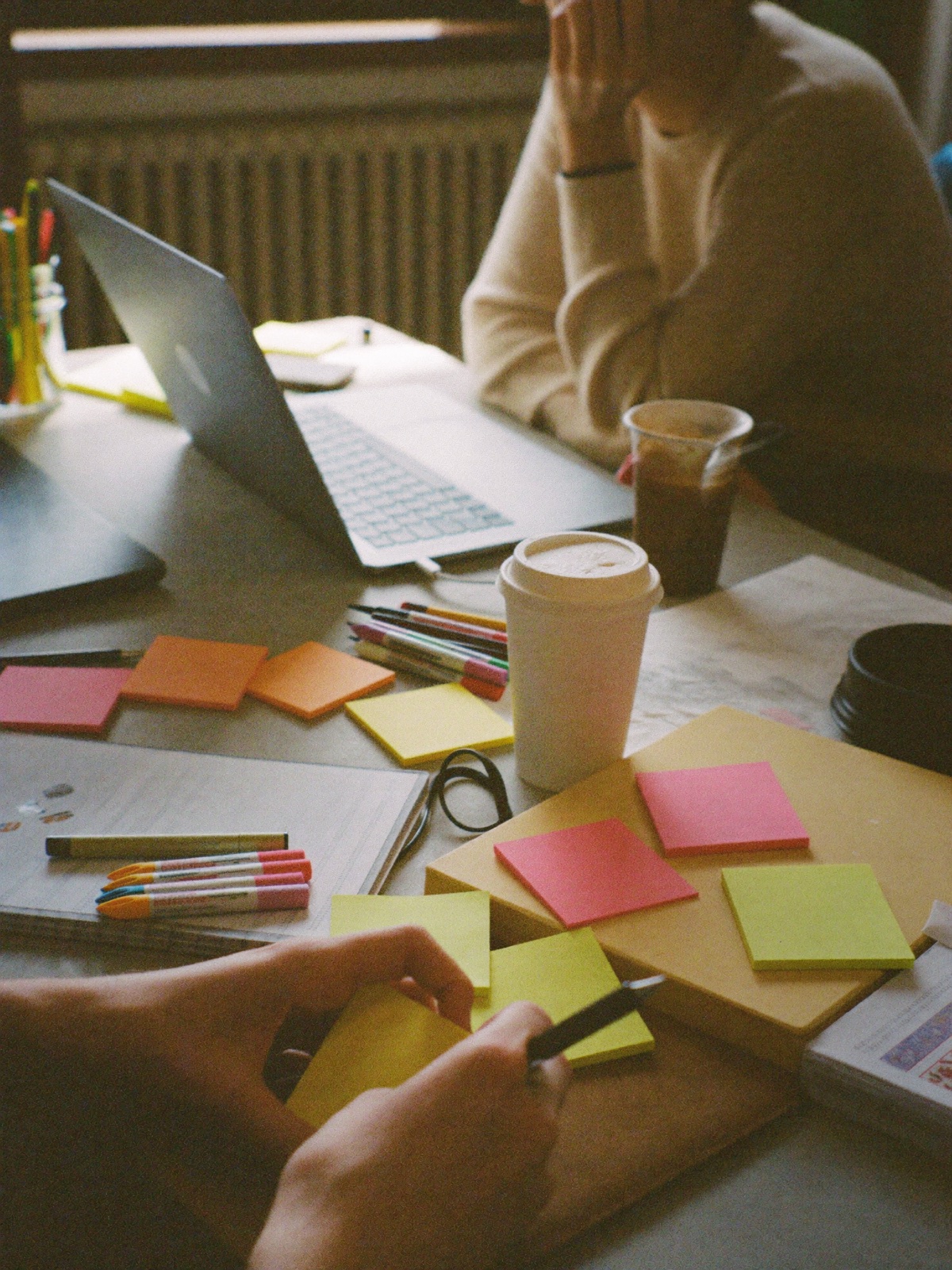 Close-up of a team working through ideas on sticky notes beside a laptop